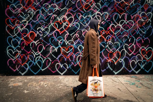 A photo of a man walking in front of heart graffiti